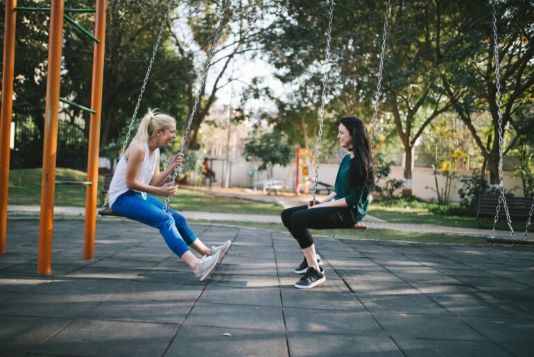 two girls on a swing chatting